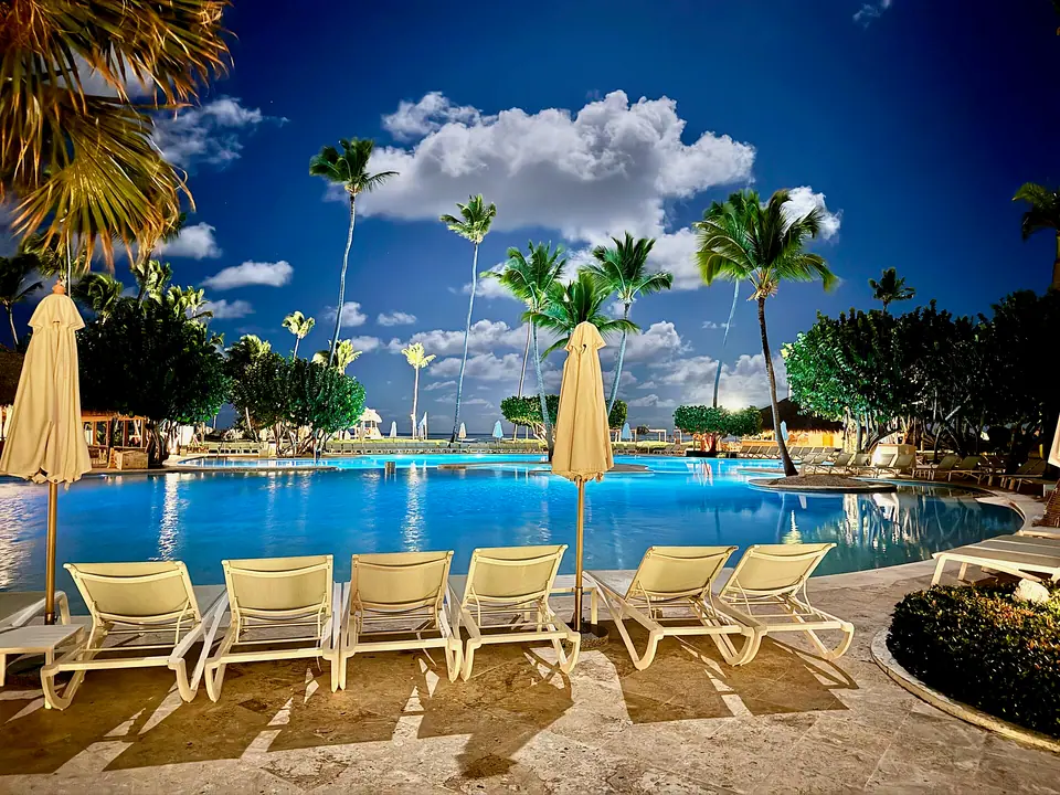 Lounge chairs and yellow umbrellas beside a large blue pool lined with palm trees at Iberostar Selection Bávaro Suites
